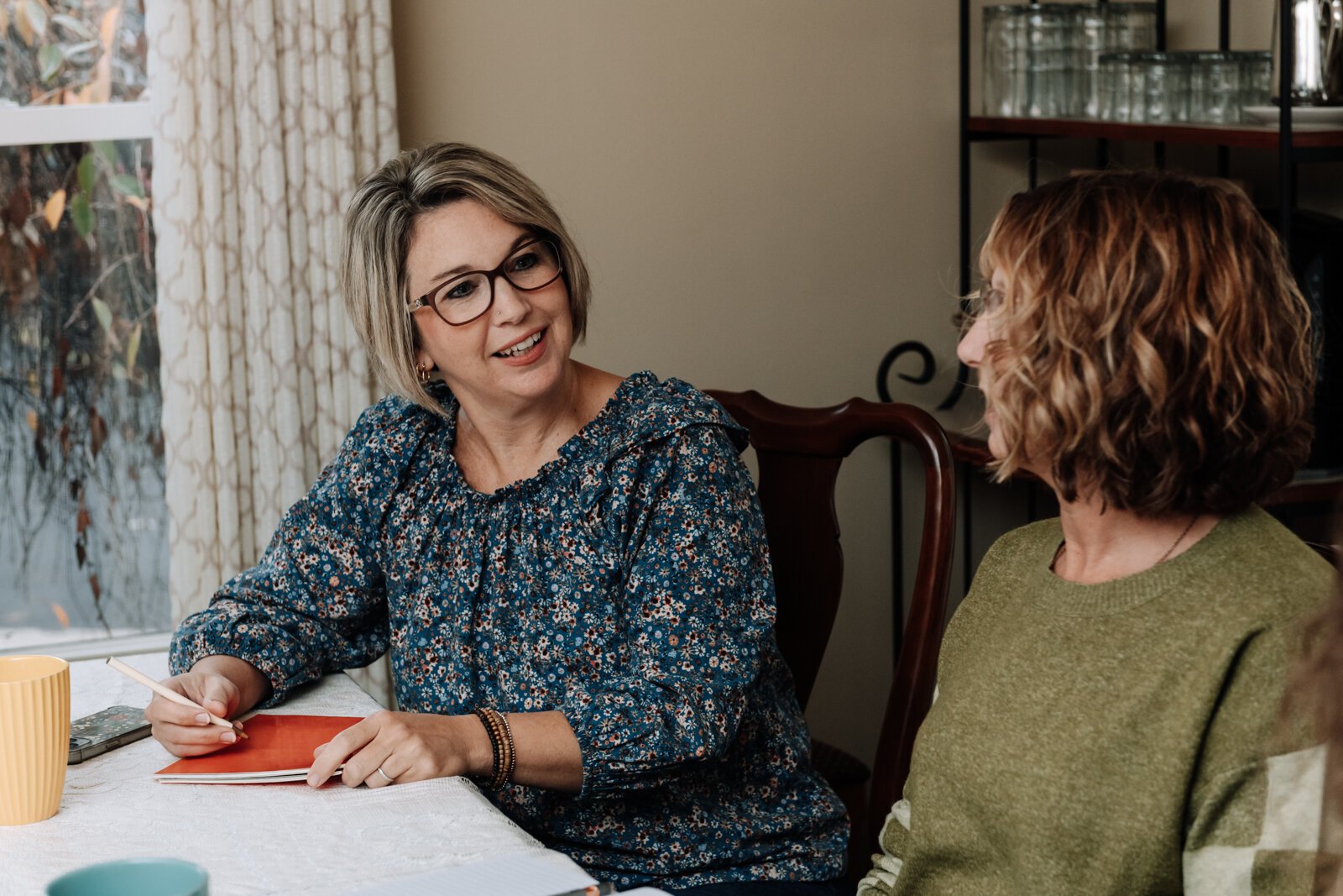 Heather Morris, director of outreach and operations, and Ann Heign, executive director talk during an International House staff meeting.