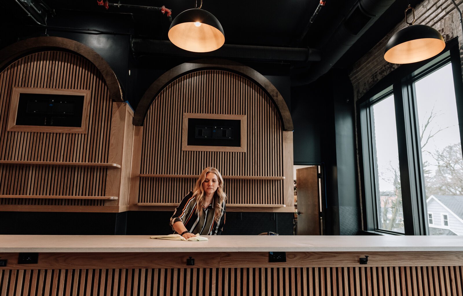 Nicole Derheimer wipes down the bar area at Urban Golf on the 2nd floor at The Fairfield, 1510 Fairfield Avenue.